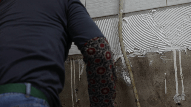 Worker applying adhesive to a wall