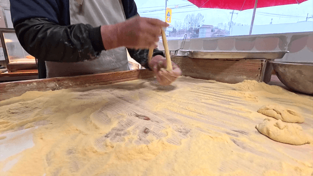 밀가루 위에서 꽈배기를 빠르게 마는 제빵사