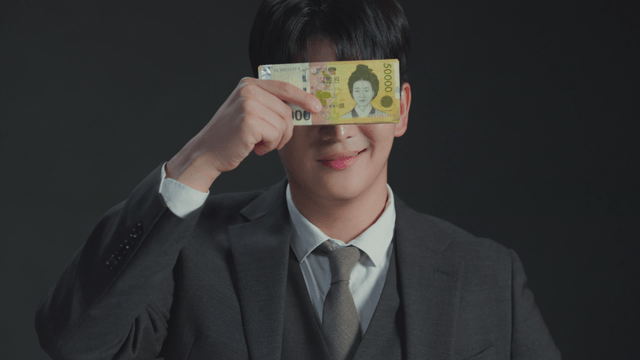Man showing mixed expressions while covering his face with money