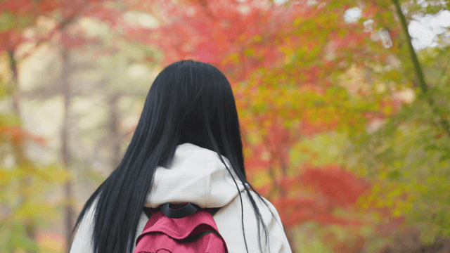 Long-haired woman walking through autumn forest