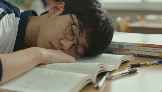 Student sleeping on a textbook in class