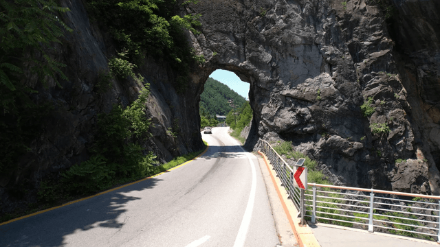 Road passing through rocky tunnel with car