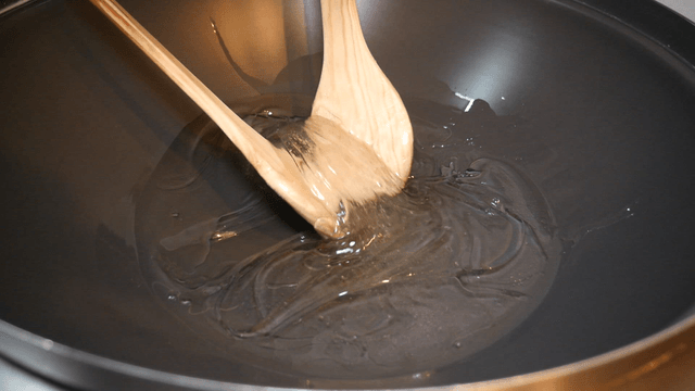 Wooden spatulas stirring honey in a pan