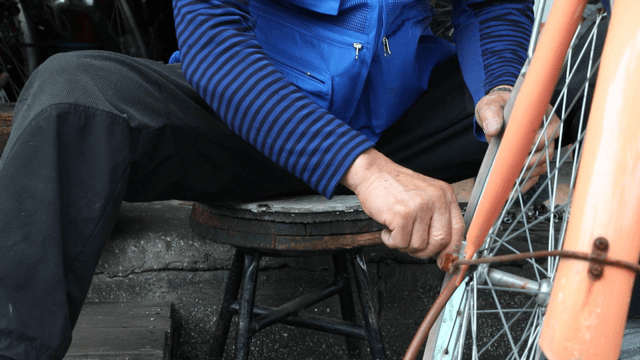 Person repairing a bicycle wheel outdoors