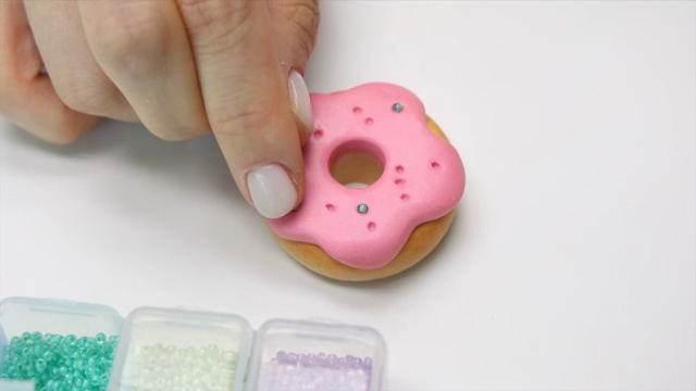 Hands shaping a donut out of clay
