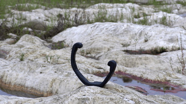 Black wooden sculpture on rocky terrain