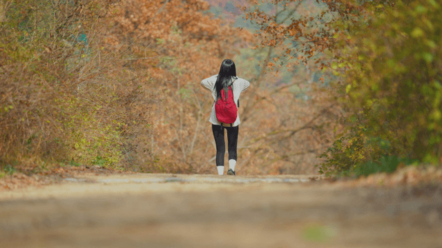 Young woman descending autumn mountain trail