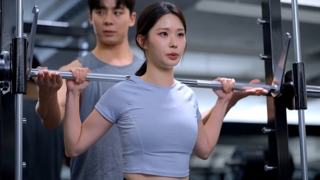 Young woman lifting weights with a trainer
