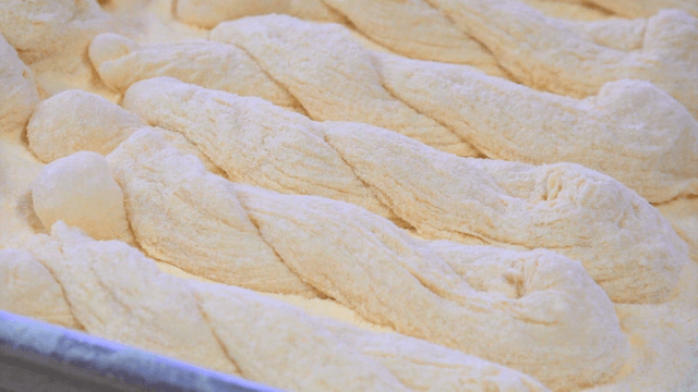 밀가루를 뿌린 표면에 놓인 꼬인 꽈배기 반죽