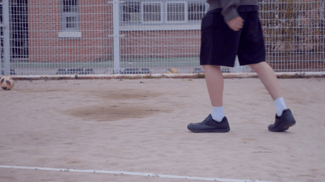 모래 운동장에서 축구를 하는 사람