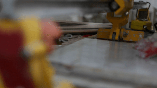 Worker operating a tile cutting machine