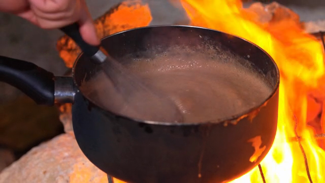 Stirring chocolate batter in a saucepan over a fire