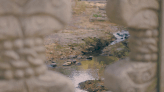 Stone carvings with a stream in the background