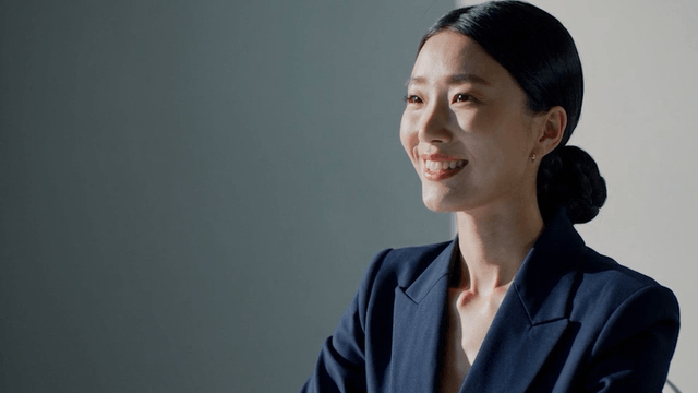 A woman in a blue suit smiling indoors