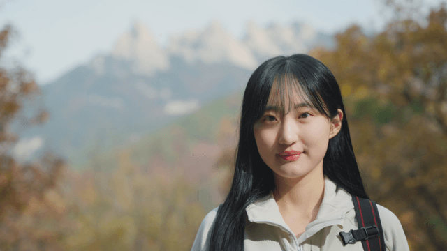 Young woman standing before autumn mountain