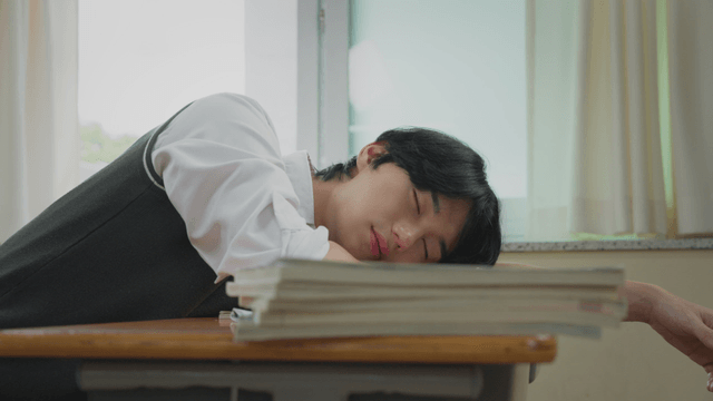 Student sleeping on a desk in a classroom