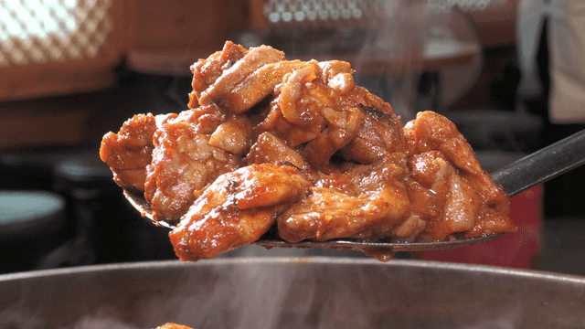Spicy stir-fried chicken scooped with a spatula from the pan