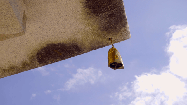 맑은 하늘 아래 돌에 매달린 전통 풍탁 종