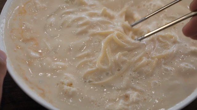 Chopsticks lifting noodles in a bowl