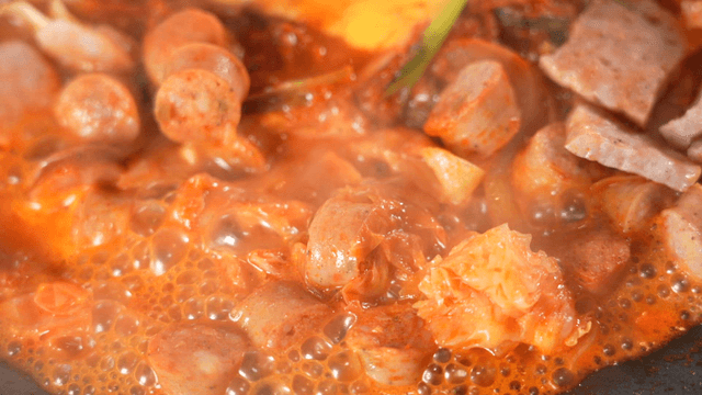 Boiling budaejjigae topped with cheese and vegetables