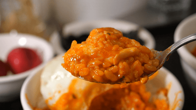 Spoon of rice mixed with fried egg and kimchi stew broth