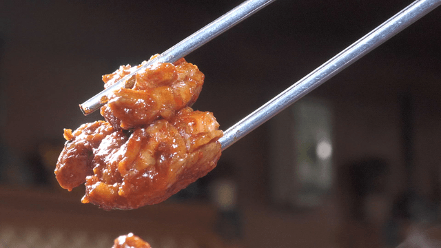 Chopsticks holding spicy stir-fried chicken