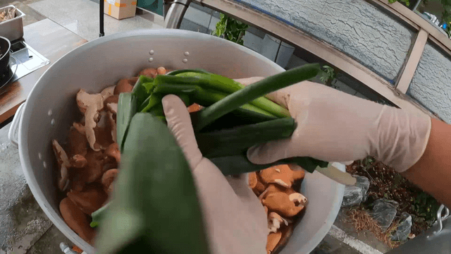Adding green onions to a pot with mushrooms