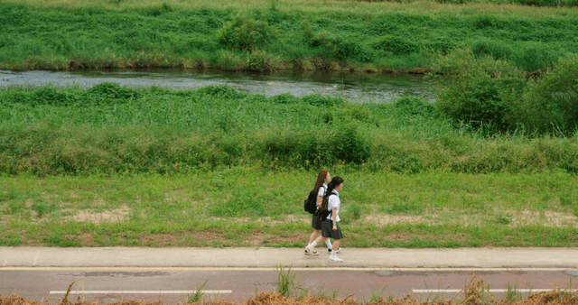 Two students walking by the riverside trail sharing earphones