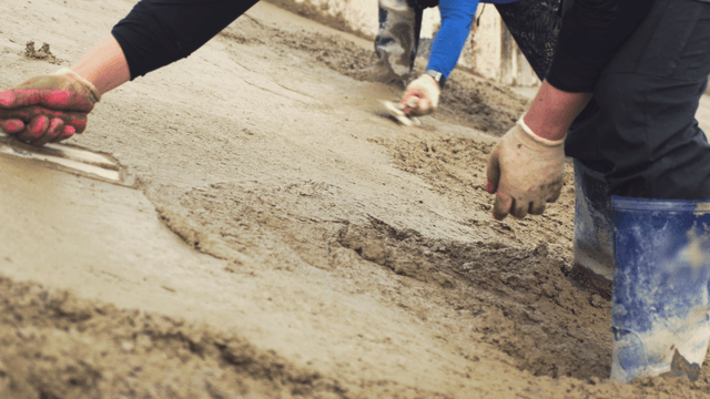 Workers smoothing wet concrete with tools