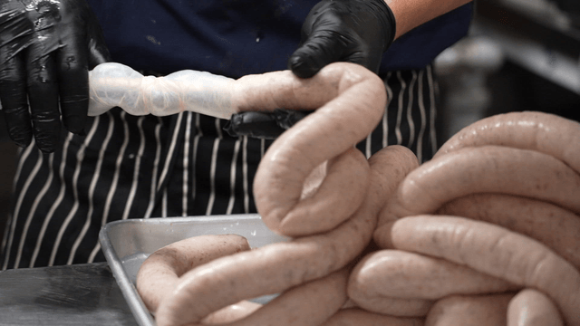 Chef stuffing sausage casing in kitchen