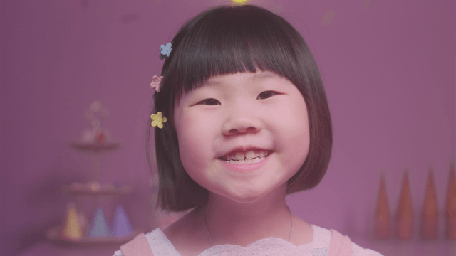 Young girl wearing colorful hairpins and speaking while looking straight ahead