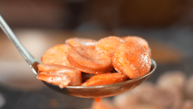Ladle filled with stir-fried sausage