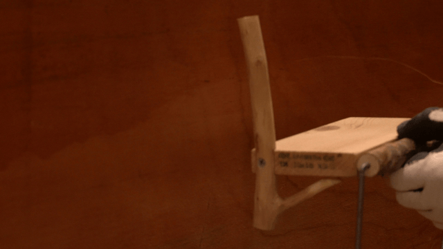 Hand positioning a wooden toilet paper holder on the wall