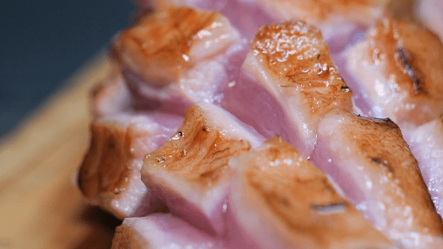 Grilled pork jowl full of juice on a cutting board