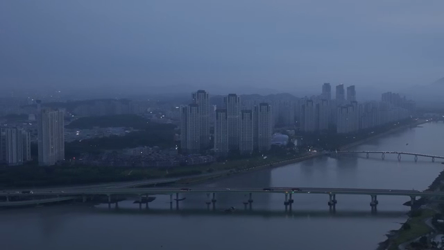 A city skyline with a river at dusk