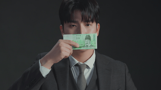 Man covering his mouth with money