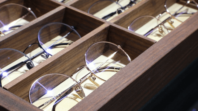 Display of various eyeglasses in a wooden case