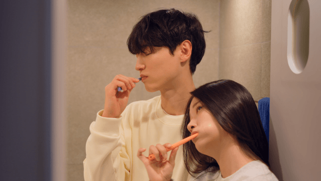 Couple brushing teeth together leaning on each other