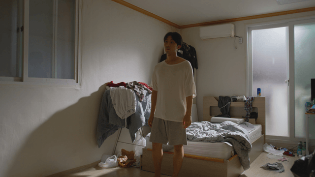 Man standing in a messy bedroom