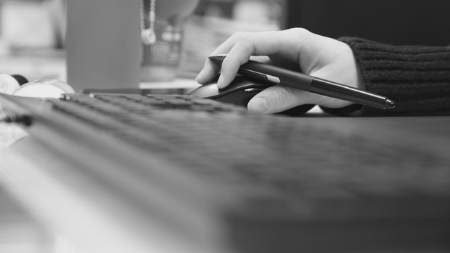 Hand holding a pen on a computer mouse