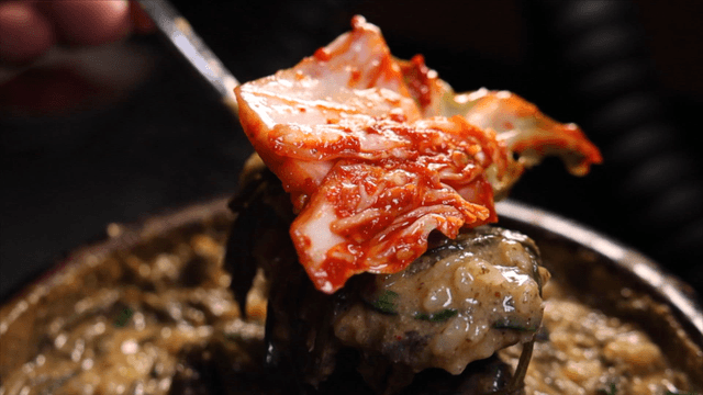 Spoon topped with loach soup and kimchi