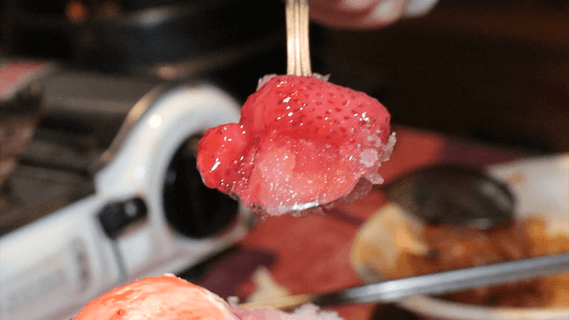 A spoonful of shaved ice topped with strawberries