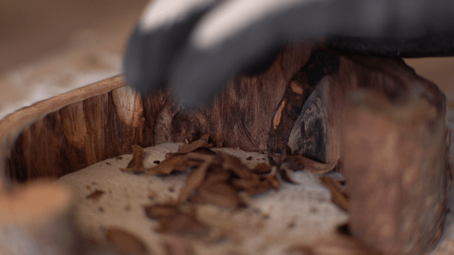 Woodcraft artisan carving a wooden piece on fabric