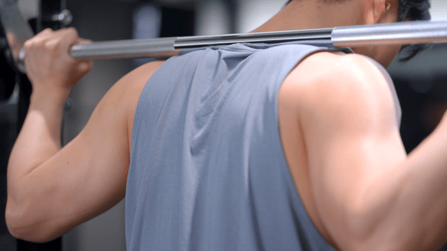 Man performing squat with weighted bar on shoulders