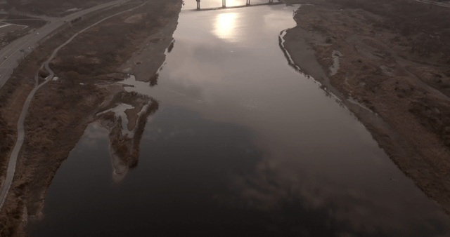 A tranquil river with a bridge at sunset