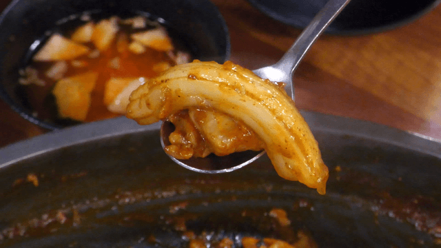 Spoon holding stir-fried chicken and glass noodles