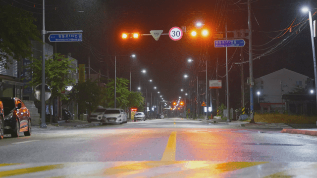 Empty road with orange traffic light at night