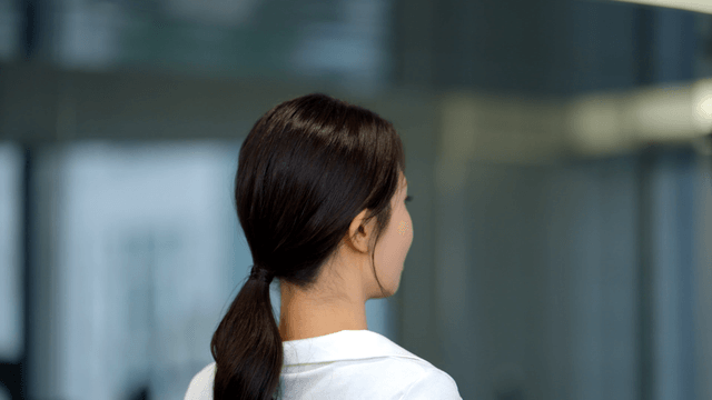 Young woman smiling back while adjusting tied hair