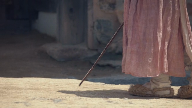 A person walking wearing a hanbok and straw shoes