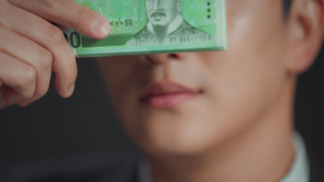 Man smiling with his eyes covered by money